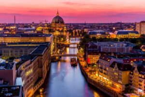 Panoramic aerial view of Berlin skyline with famous TV tower and Spree river at sunset.