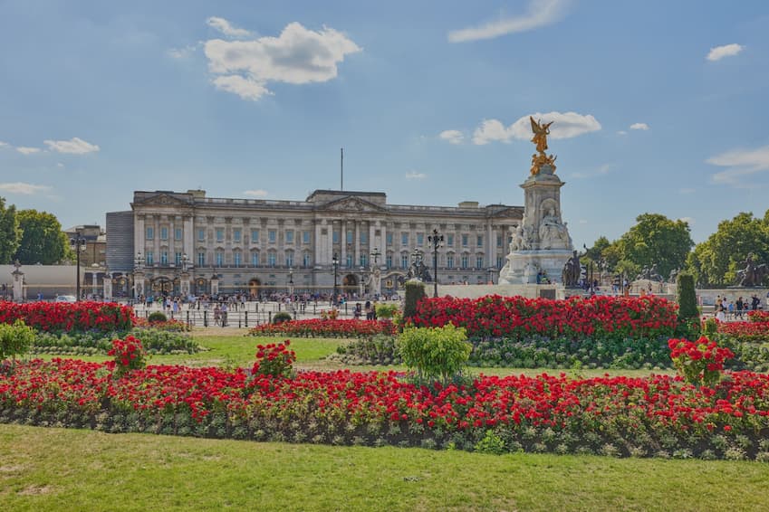 Buckingham Palace with flower beds in front on a sunny day in London.