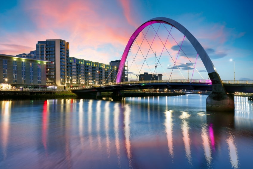 Colorful night view of modern bridge in Glasgow, symbolizing the rivalry and connection with Edinburgh.
