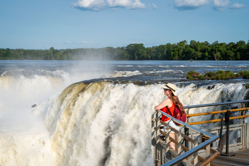 Young tourist enjoying the view of Devil's Throat at Iguazú Falls, Argentina — a breathtaking stop before 3 days in Toronto.