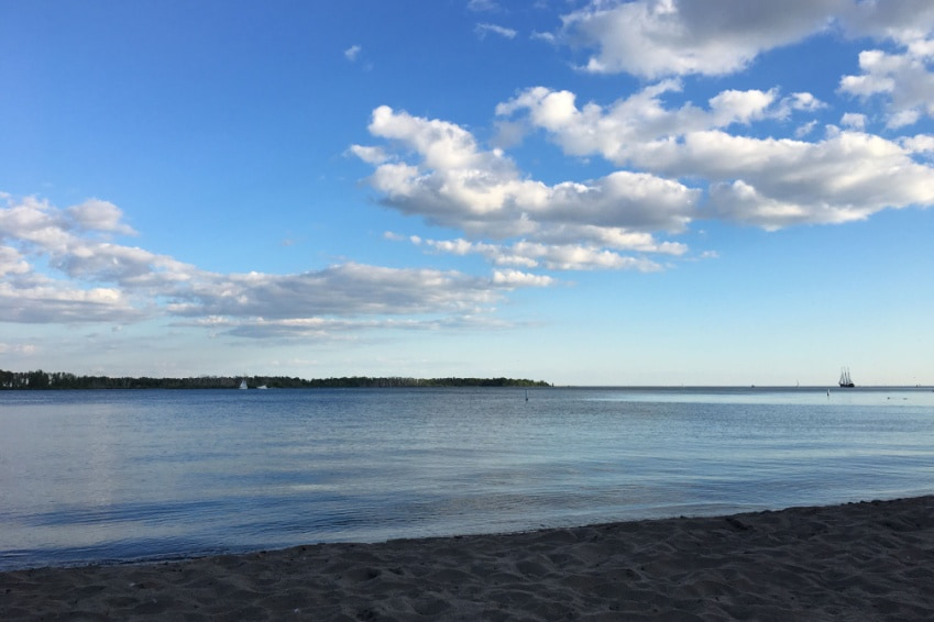 Wide sandy stretch at Cherry Beach with gentle waves under a bright blue sky.