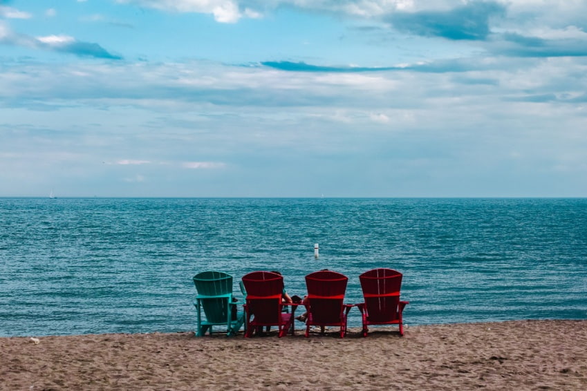 Relaxing scene at Kew-Balmy Beach with several deck chairs and a sandy shoreline and gentle lake waves.
